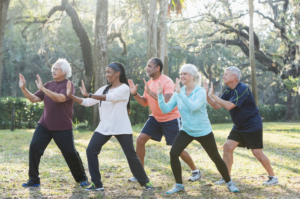 A group of people excercising together outside on a sunny day.